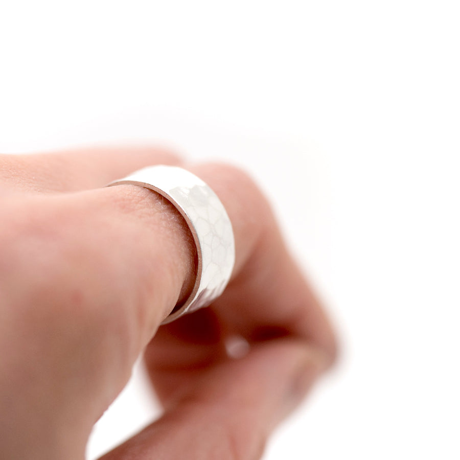 Silver ring with hammered texture on a finger