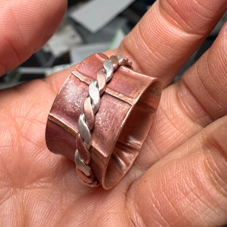 Copper ring with braided design on a person's finger_MorphiArtForge_Fidget